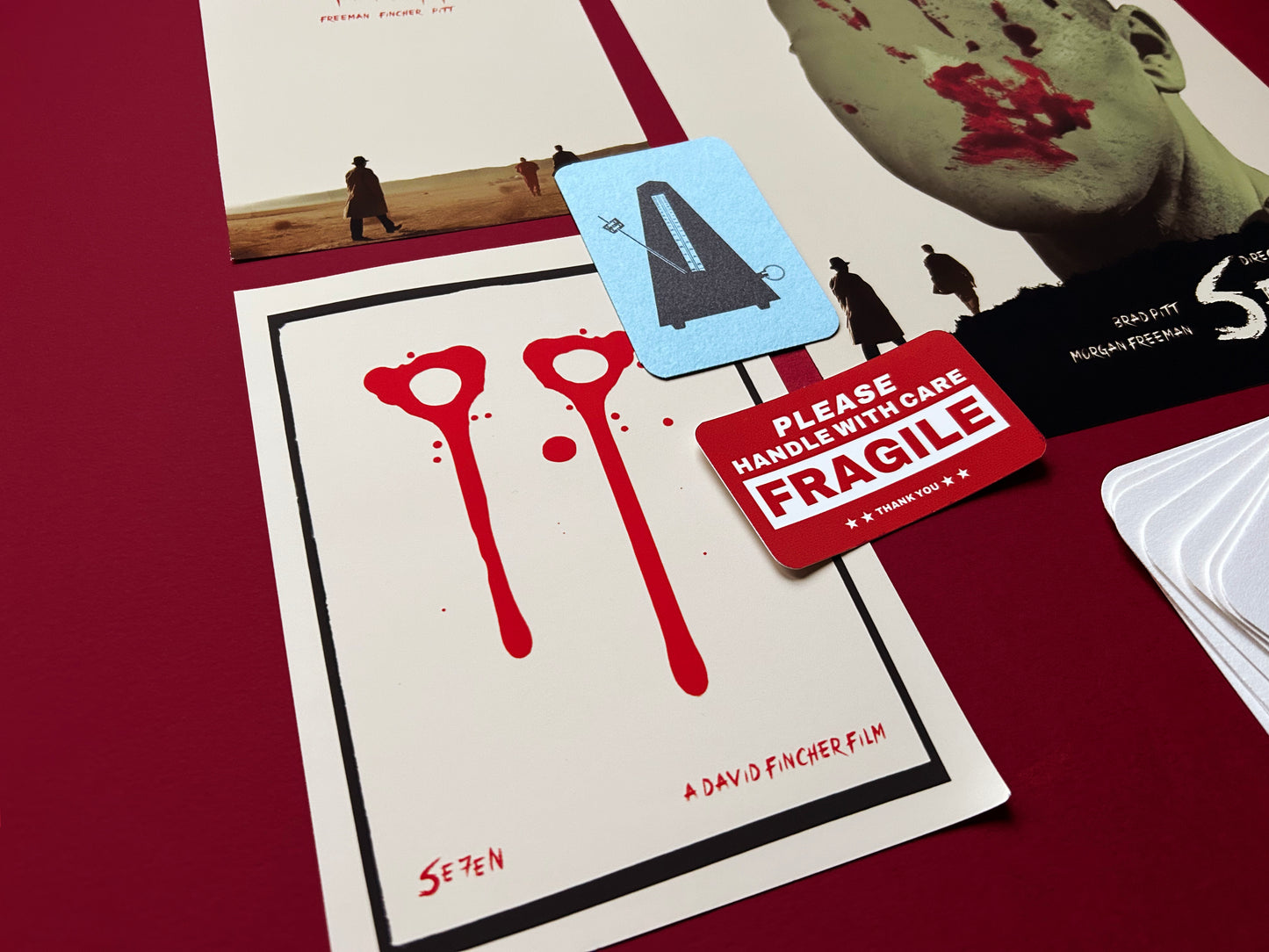 Movie poster for 'Seven' with a 'Please Handle with Care' and 'Fragile' label. This limited edition Se7en print pack is a tribute to David Fincher’s iconic masterpiece. Each set includes three fine art prints, a seven mini print booklet, a small metronome card and a collector’s sticker. This is all handmade and printed by myself.