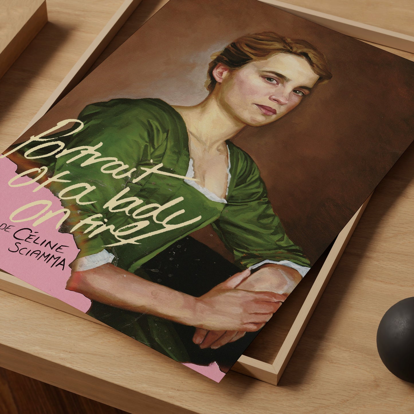 Book titled 'Portrait of a Lady on Fire' by Céline Sciamma on a wooden surface