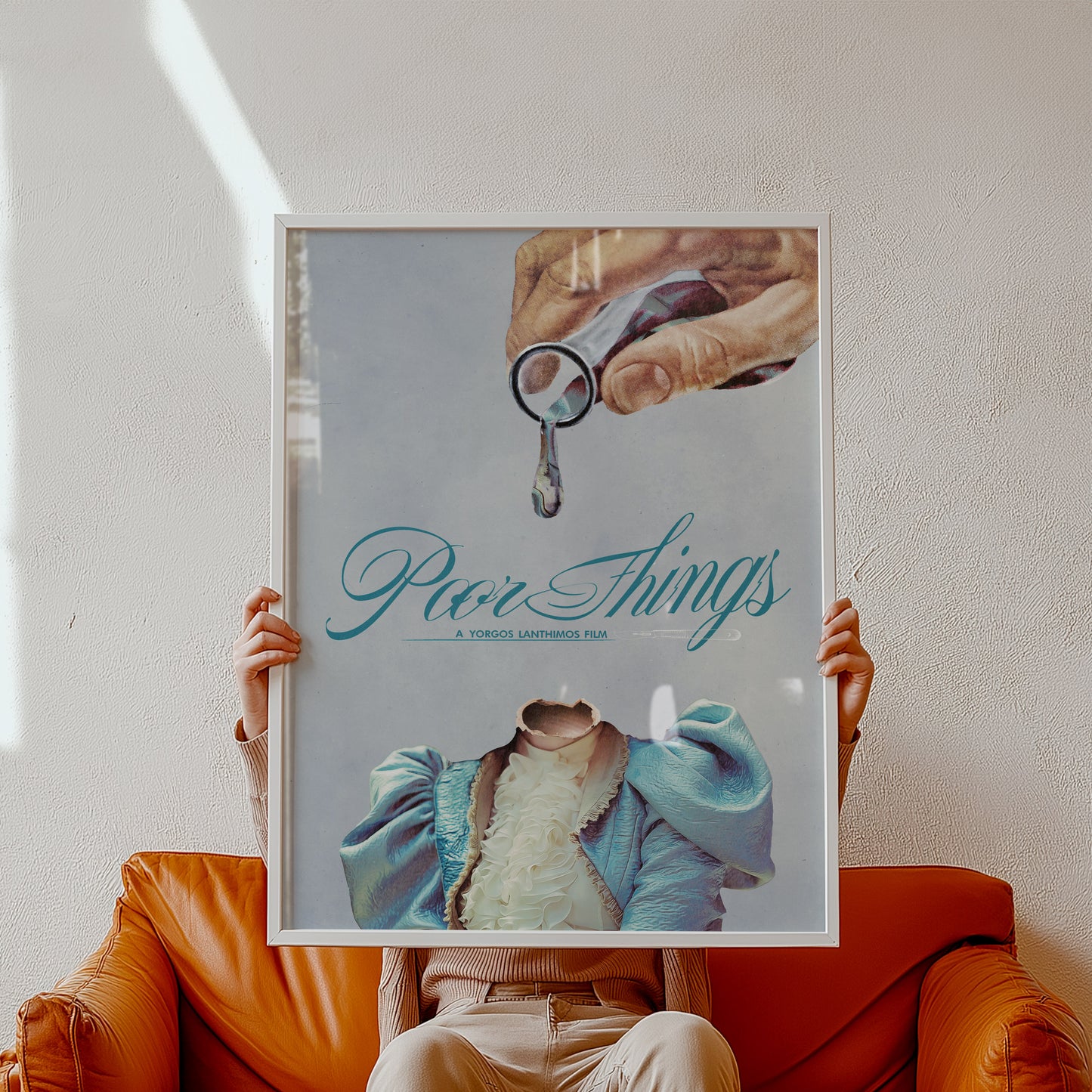 Person holding a framed poster with 'Poor Things' text and a hand holding 