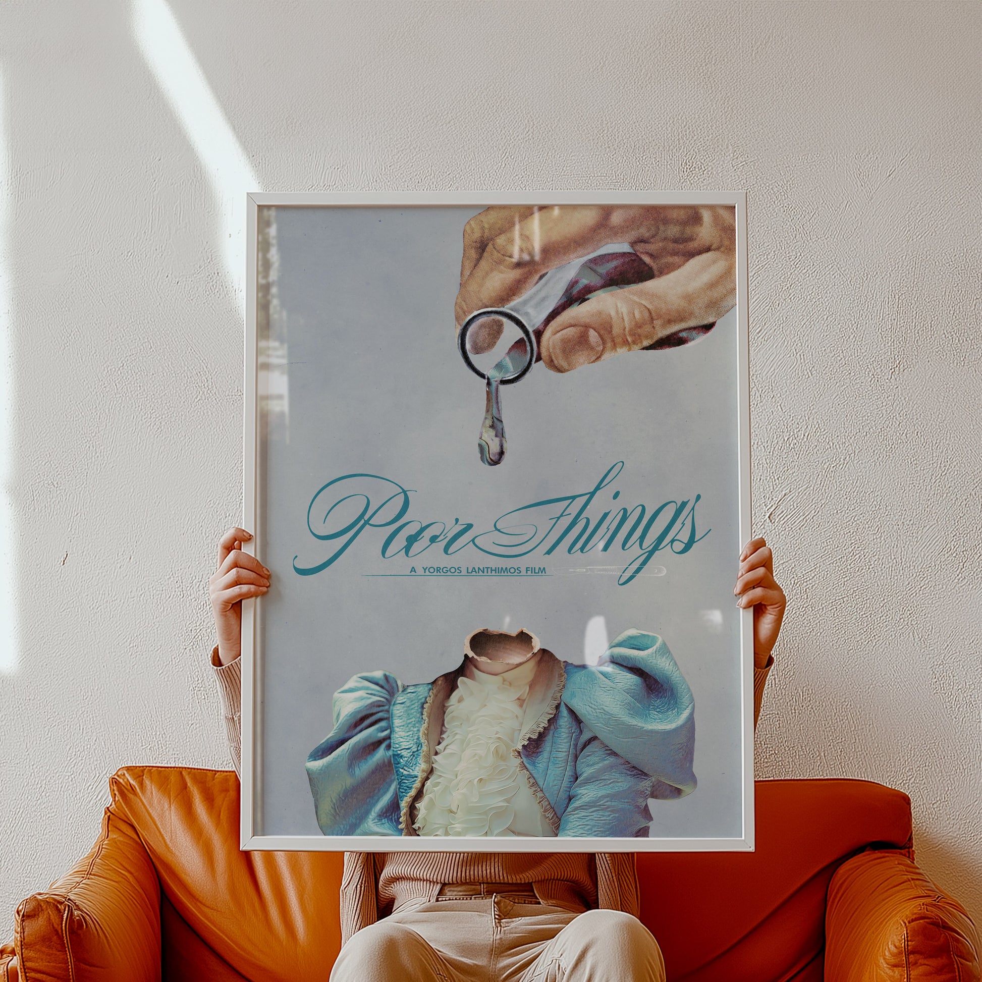 Person holding a framed poster with 'Poor Things' text and a hand holding 