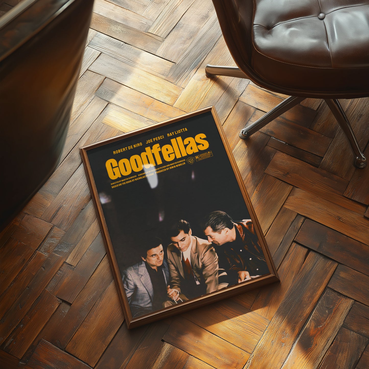 Framed 'Goodfellas' movie poster on a wooden floor with a chair in the background